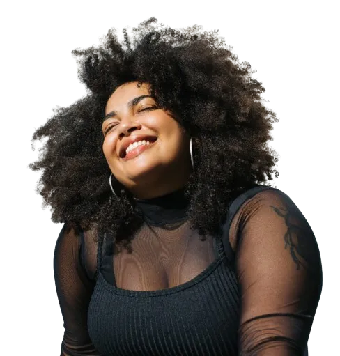 A woman in a black sheer shirt smiling with the sun shining on her face.